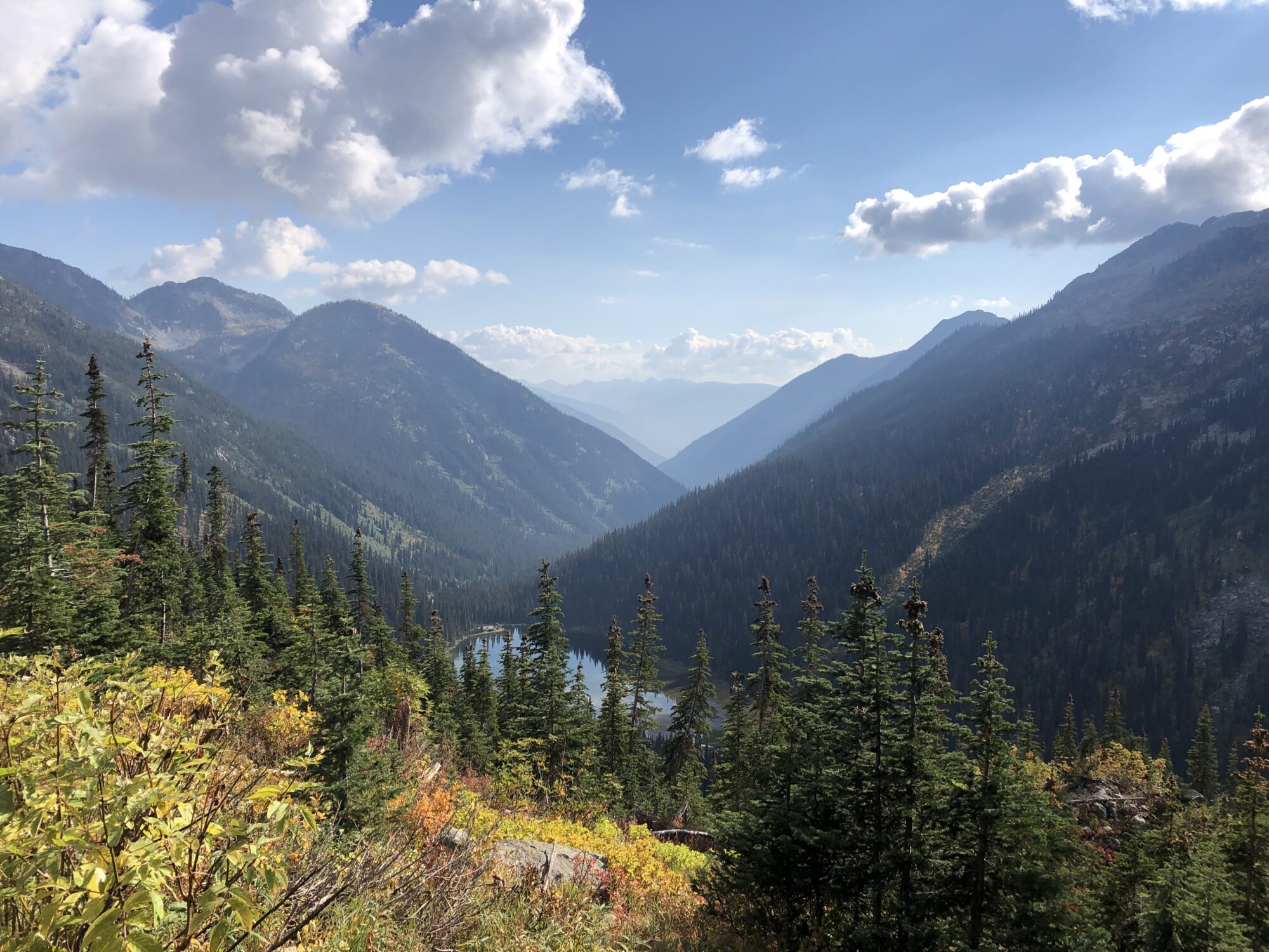 View of mountains in the fall with coloured leaves all around and a small lake in the centre